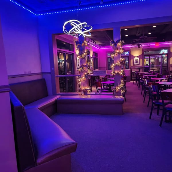 Shades Bar & Grill interior with purple and blue lighting, booths, tables, and festive garland decorations.